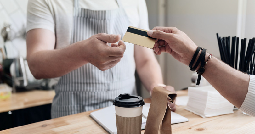 Two people execute a sale by exchanging a credit card for payment.