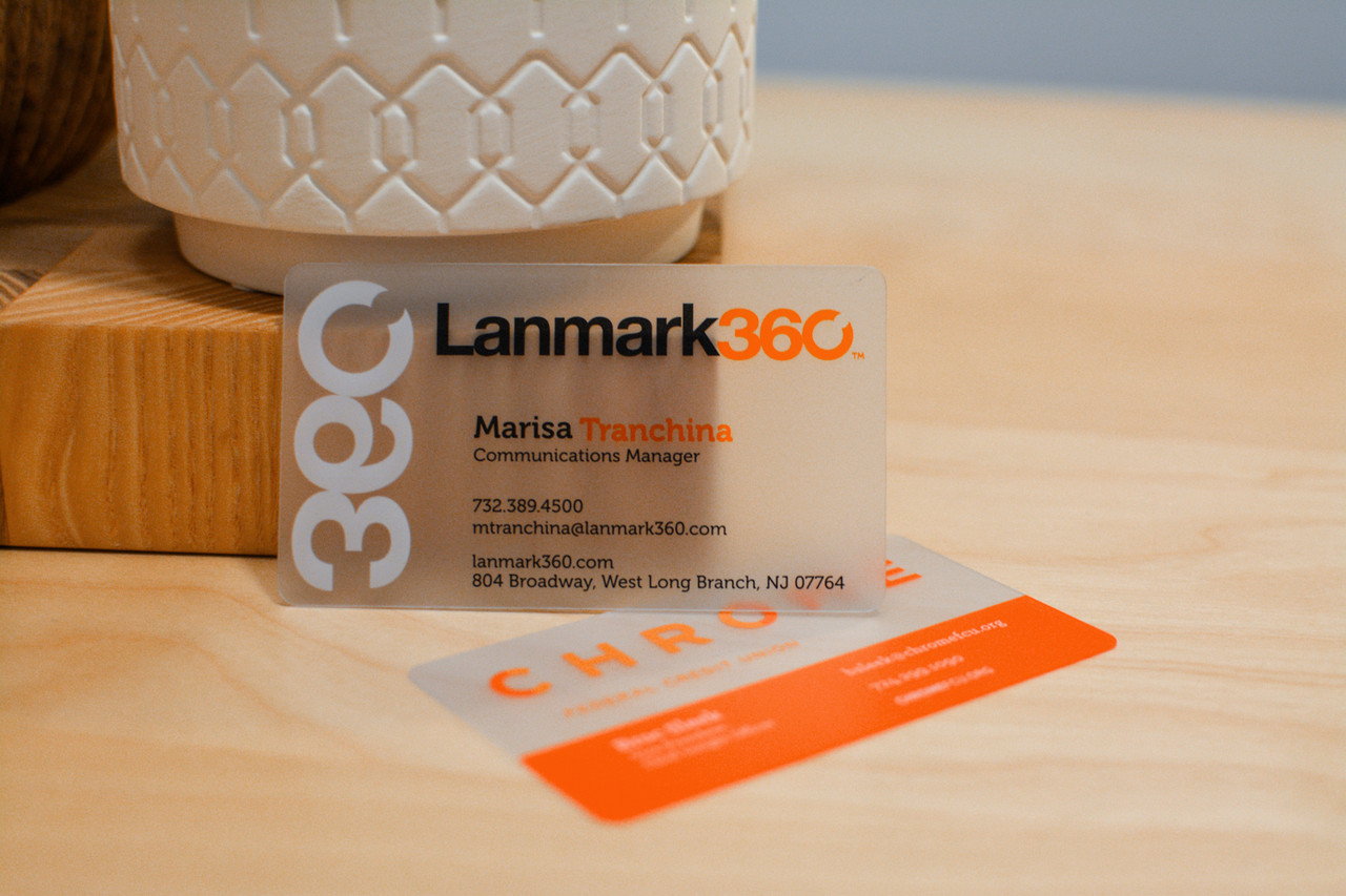 A single plastic business card printed on clear plastic with a vase visible behind