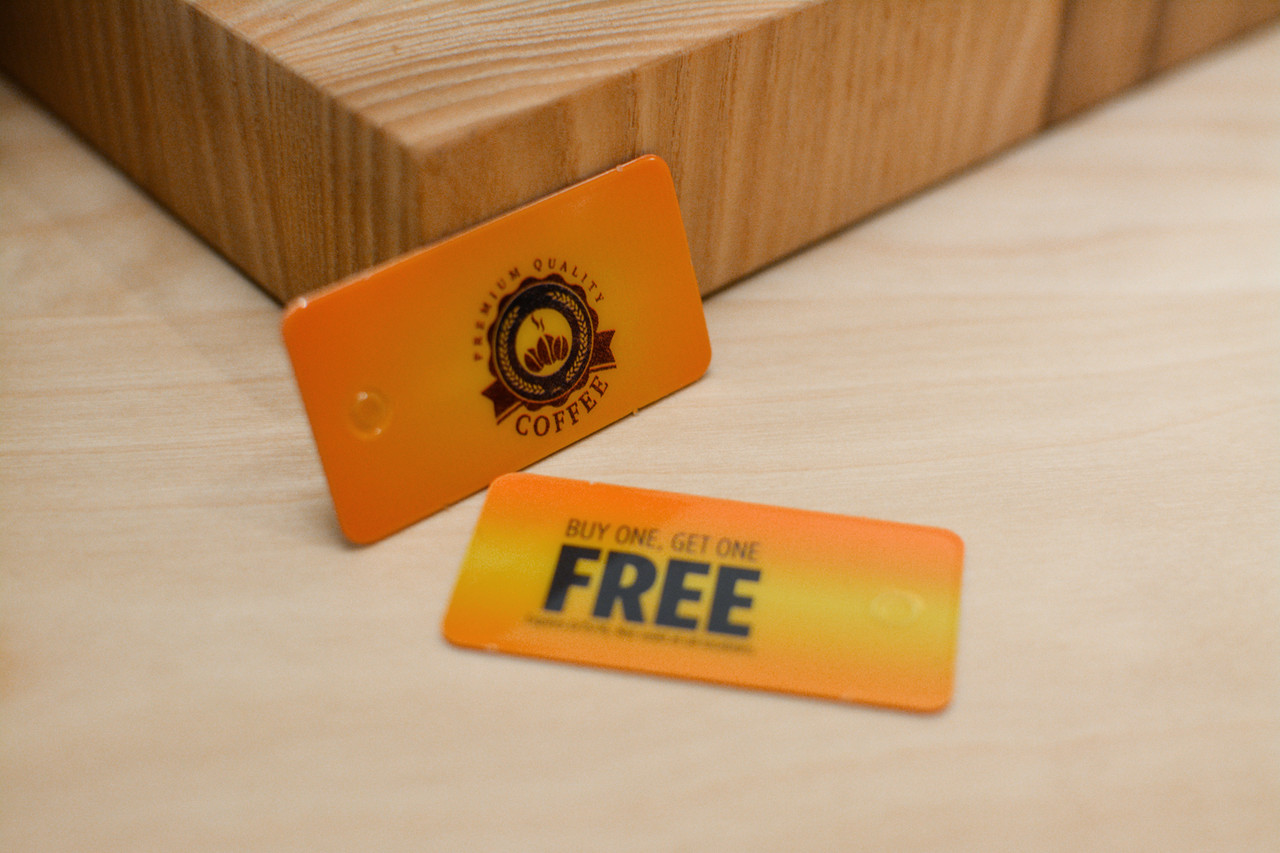 A small pile of orange and yellow coffee shop key tags that offer a buy on coffee and get another one free deal