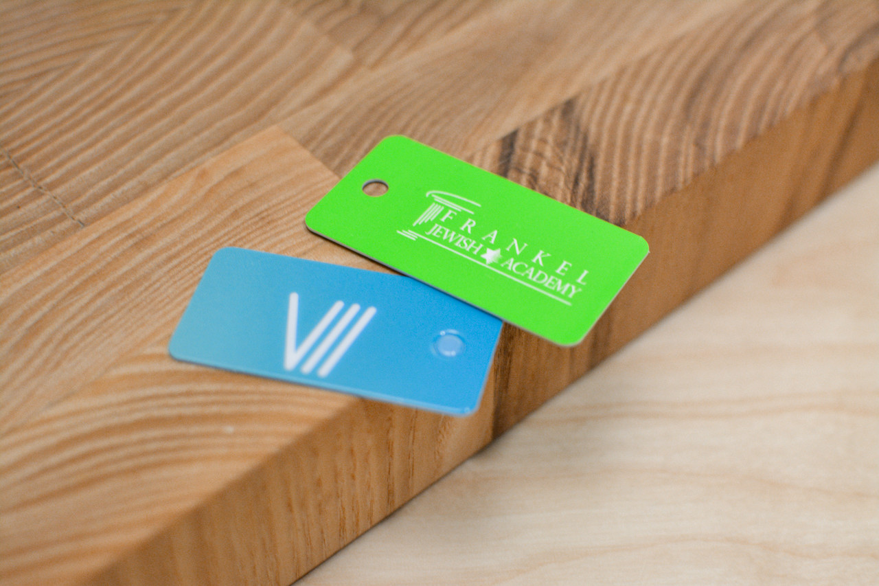 Three different key tag designs used by restaurants and schools that feature bright colors