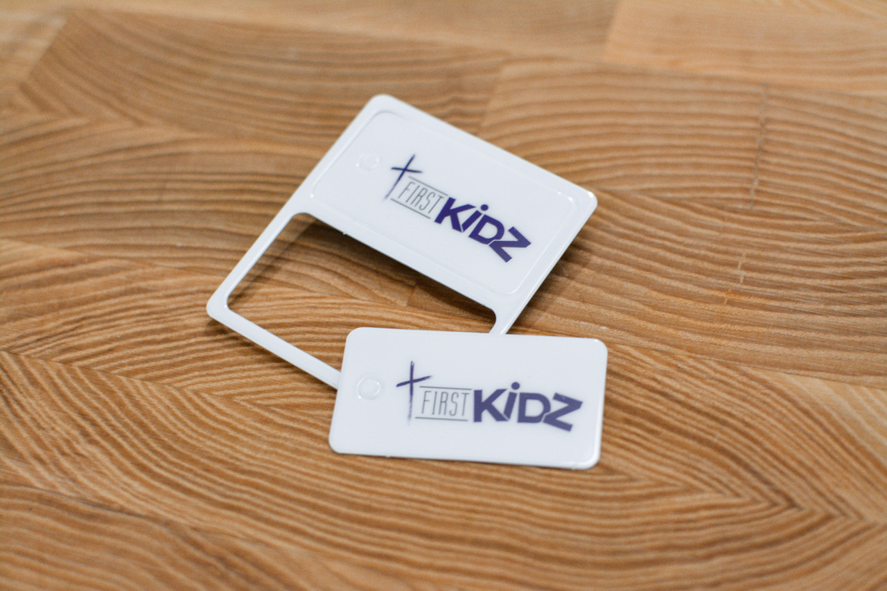 A plastic card and plastic key tag still attached together with a first aid design theme